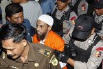 Accused bomb maker Umar Patek is shown being escorted to court at the start of his trial in West Jakarta, February 13th. His defense team argues that he was not part of the plot to unleash mass murder in Bali. [Reuters]