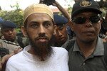 Tersangka perakit bom Umar Patek tampak dikawal ketat oleh polisi di Bali, Oktober 2011, selama peragaan pemboman Bali tahun 2002. Dalam kesaksian pada tanggal 22 Maret, saksi Idris bersaksi bahwa jaringan al-Qaeda yang dipimpin Osama bin Laden mendanai misi pemboman itu, menyalurkan $30.000 ke pemimpin regional Jemaah Islamiyah, Mukhlas. [Zul Edoardo/Reuters]