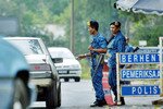 Malaysian police man a checkpoint near the Malaysia-Thailand border in the village of Jeram Perdah, about 550km (340 miles) northeast of Kuala Lumpur. Human traffickers try to sneak illegal immigrants stowed in trucks and car boots into both countries. [Bazuki Muhammad/Reuters]