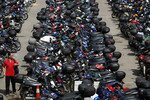Seorang pria berjalan melewati ratusan sepeda motor di Johor Bahru. Para pembalap motor “Mat Rempit” telah menyebabkan kecemasan karena diduga mengintimidasi para pengendara motor dan pejalan kaki. [Nicky Loh/Reuters]