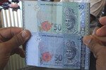 Salah satu uang kertas palsu (bawah) bernilai 50 Ringgit Malaysia ($15,79) yang diduga digunakan layaknya uang asli oleh terdakwa pemalsu uang Somkiat Oo-seng. Uang kertas 50 ringgit asli ditunjukkan di atasnya. [Adinan Malee/Khabar] 