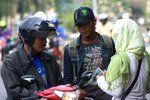 Rukmiyati, 34, and her customers do a money transaction on Jalan Gajah Mada in Central Jakarta on August 14th. Despite the fee charged, many Indonesians visit street peddlers to exchange their large bank notes for small ones for gift giving on Idul Fitri.[Elisabeth Oktofani/Khabar].