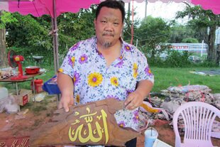 Jaofat Srisombat datang dari Chiang Mai untuk menjual ukiran kayu jati buatan tangan bertuliskan pesan-pesan agama.