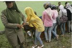 Seorang polisi wanita Syariah mengawal para wanita muda yang mengenakan celana jins ketat selama pemeriksaan jalanan di Banda Aceh. Jins dianggap sebagai pakaian tidak senonoh oleh umat Muslim yang konservatif. [Tarmizy Harva/Reuters].