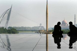 Para pekerja istirahat siang di teras yang menghadap masjid dan jembatan Putrajaya di bulan Maret 2011. Malaysia telah dinilai sebagai tujuan wisata Muslim terbaik di dunia berkat tempat sholat yang berlimpah, pilihan makanan halal dan rasa nyaman bagi wisatawan Muslim. [Saeed Khan/AFP]