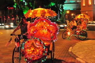 Lampu-lampu meriah menarik para wisatawan untuk keliling di bawah sinar bulan dengan becak di Melaka, kota bersejarah di Malaysia. [Grace Chen/Khabar]