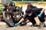 Penyidik polisi mengumpulkan bukti dari lokasi ledakan, di samping sepeda motor rusak yang digunakan oleh seorang pembom bunuh diri yang menyerang markas polisi di Poso, Sulawesi pada tanggal 3 Juni. Polisi yakin bahwa orang tersebut adalah anggota dari sebuah kelompok teror Islam yang berafiliasi dengan ekstrimis terpenjara, Abu Omar. [Olagondronk/AFP]