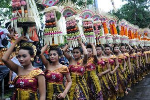 Para wanita Bali membawa persembahan di parade pada hari pembukaan festival pada 15 Juni. [Sonny Tumbleka/AFP]