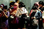 Passengers travelling home for Idul Fitri wait to board at the Senen train station in Jakarta on August 7th. Many are busy using their cell phones to wish friends and family a happy holiday. [Arif P/Khabar]