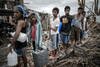 Para korban selamat Haiyan mengantri untuk mendapat air minum di Palo, pinggiran Tacloban, pulau sebelah timur Leyte pada tanggal 17 November 2013. ASEAN dan Amerika Serikat telah bekerja untuk menjangkau jutaan korban dengan pengiriman makanan, air, dan obat-obatan. [Philippe Lopez/AFP]