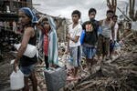 Para korban selamat Haiyan mengantri untuk mendapat air minum di Palo, pinggiran Tacloban, pulau sebelah timur Leyte pada tanggal 17 November 2013. ASEAN dan Amerika Serikat telah bekerja untuk menjangkau jutaan korban dengan pengiriman makanan, air, dan obat-obatan. [Philippe Lopez/AFP]