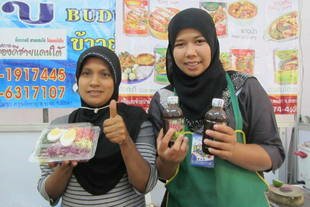 Mayuree Niyomdecha (left), from Chana District of Songkhla, displays Halal products made by a house-wives co-operative in her village, at the One Tambon One Product (OTOP) fair in Phuket in late November. Participating in OTOP fairs has given her the chance to travel around Thailand. [Somchai Huasaikul/Khabar]