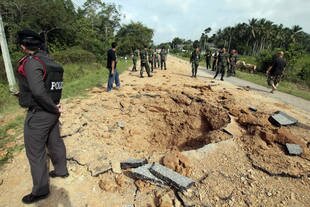 Thai policemen and soldiers gather at the site of a roadside bombing in Pattani province that killed five soldiers and wounded at least nine others on Wednesday (December 11th). A hidden 50-kg bomb blew up as an army vehicle approached. [AFP]