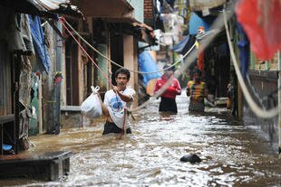 Jakarta residents wade through a flooded neighbourhood Monday (January 20th). [Adek Berry/AFP]