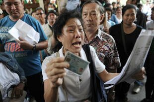 A frustrated voter holds her national identification card and shouts at police after anti-government protesters prevented delivery of election material in Bangkok on Sunday (February 2nd). [Christophe Archambault/AFP]