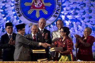 MILF peace panel chief Mohagher Iqbal shakes hands with government chief negotiator Miriam Coronel Ferrer during the signing of the Comprehensive Agreement on the Bangsamoro at the Malacanang Palace in Manila on Thursday (March 27th). [Noel Celis/AFP]