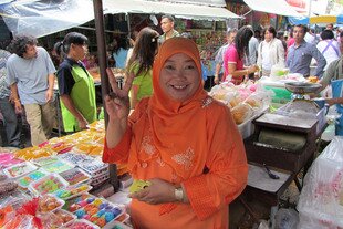 A sweets vendor flashes a peace gesture at the Thepwiwat 1 Municipal Fresh Market on Friday (October 19th). [Bas Pattani/Khabar]