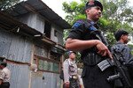 Police stand outside a building in West Java that was raided by Detachment 88 earlier in the day (March 15th). Five men found inside were involved in the recent robbery of a gold store to raise money for terrorism, authorities say. Two suspects were killed in the raid. [Stringer/Khabar].