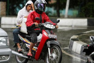 An Acehnese woman rides on the back of a motorcycle in Banda Aceh. After crackdowns on women straddling motorcycles, authorities in North Aceh were criticised by women's rights groups Saturday (May 25th) for a new restriction banning area women from dancing in public places. [Chaideer Mahyuddinna/AFP]