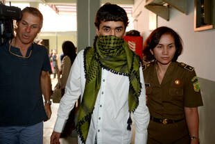 An Indonesian official guards Afghanistan national Sayeed Abbas prior to his Thursday (July 11th) trial at a South Jakarta court. The court released the alleged human-trafficking kingpin, rejecting an Australian request for extradition. [Adek Berry/AFP]