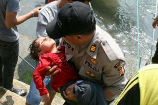 A policeman carries an exhausted young boy following a search and rescue effort in Cidaun, West Java on Wednesday (July 24th). About 157 people were saved, while at least 15 others died after a boat carrying approximately 200 asylum-seekers sank off Indonesia on Tuesday. Rescue workers said Friday it was unlikely more survivors would be found. [AFP]