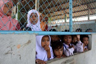 Kindergarten and primary students at Ban Taopoon School look on after suspected insurgents detonated an improvised explosive device (IED) on the campus in Yala's Bannang Sata district Wednesday (July 31st). Two security officers were injured in the attack. [Ahmad Ramansiriwong/Khabar]