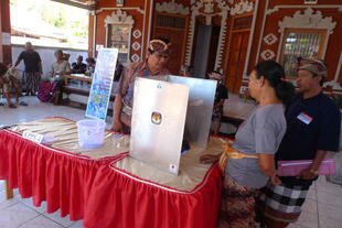Election workers assist Wayan Ngidep during e-voting at Mendoyo Dangin Tukad village in Bali on July 29th. [Ni Komang Erviani/Khabar]