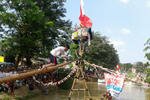 An East Jakarta teenager balances as he makes his way to the end of a betel nut palm tree bridge placed across the Kalimalang River. In this cherished local tradition, held during Independence Day celebrations, participants are given a chance to cross the bridge and collect gifts placed at its end. [Zahara Tiba/Khabar].