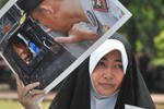 During a May protest, a Shia woman holds a photo showing followers of Ahmadiyah locked inside their mosque in Bekasi. Indonesian authorities say they will not bow to demands for a ban on the sect. [Adek Berry/AFP]