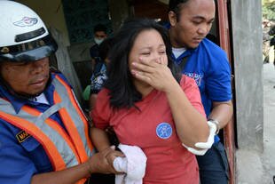 An injured Zamboanga City resident is helped by rescuers after a mortar shell believed to be fired by Muslim rebels hit her house Saturday (September 21st) as Philippine government forces clashed anew on Mindanao. [Ted Aljibe/AFP]