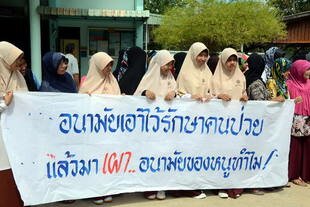 Residents of Bajoh district, Narathiwat hold a banner that reads, 