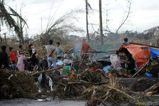 A family stand at their temporary shelter amongst the debris in Tacloban city, central Philippines on Tuesday (November 12th), four days after Super Typhoon Haiyan hit. ASEAN member nations mobilised to send financial resources and supplies to the devastated Philippines. As many as 10,000 people are estimated to have died from the storm. [Ted Aljibe/AFP]
