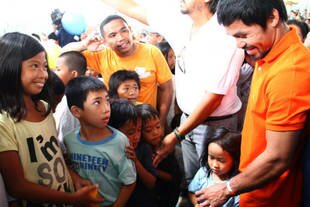 Filipino boxer Manny Pacquiao (right) visits a Tacloban evacuation centre Monday (December 2nd). Pacquiao handed out food and cash and posed for pictures with victims of Super Typhoon Haiyan. The UN announced Friday it is seeking more international aid for typhoon victims. [AFP]