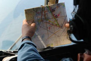 A Vietnamese Air Force helicopter crew member checks a map during a March 11th aerial search of South China Sea waters off Vietnam for a missing Malaysian airliner. Other nations such as Indonesia and India joined the international effort to find flight MH370. [Hoang Dinh Nam/AFP]