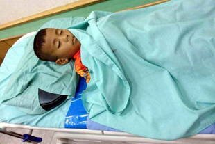 The body of 6-year old Ilayas Maman lies on a gurney at Narathiwat's Mai Kaen Hospital on February 3rd after he and his two brothers were killed in an ambush. [Rapee Mama/Khabar]