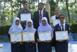 Six Yala Vocational College graduates display their certificates with Isaman Isama-air, school director. [Ahmad Ramansiriwong/Khabar]