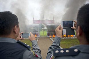 Police officers take photos of seized drugs set ablaze in Rangoon on Thursday (June 26th) to mark World Drugs Day. [Ye Aung Thu/AFP]
