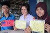  Thaksin University (TSU) in Songkhla Province freshmen (left to right) Poramin Vayo, Natchuda Samart and Pattra Leh-asan hold up signs listing nicknames and where they are from as part of "hazing week". [Samila Naranode/Khabar] 